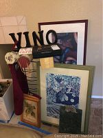 Photo showing the assembled lot with framed prints, wine opener, gift boxes, apron, wine rack, wine tags, and VINO sign.