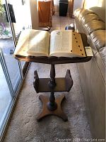 Webster's dictionary open on wooden book stand, showing front side of stand and dictionary pages.
