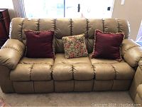Front view of tan leather sleeper sofa with four throw pillows: two burgundy, two floral.