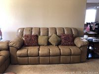 Front view of tan leather sleeper sofa with 4 throw pillows: 2 red floral and 2 solid tan.