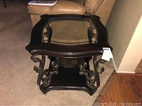 Full view of the square end table showing the dark wood top, clear glass inset and ornamental metal base with scrolled design.