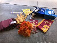 Photo showing stadium chair, foam fingers, pom-poms, mugs, jerseys and Lakers Lane sign arranged on floor.