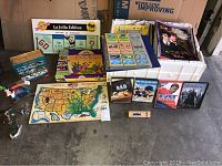 Lot items including La Jolla Edition Monopoly game, Pokemon cards in binder, several DVDs, and USA map puzzle on floor.