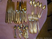 Full view of the matching community silver plated flatware set arranged on table, showing assortment of knives, forks, tablespoons, teaspoons, and smaller spoons.