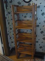 Full view of the wooden shelving unit showing four open shelves with vertical corner supports.