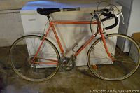 Full side view of vintage Maruishi road bicycle with orange frame, drop handlebars, and narrow road tires.