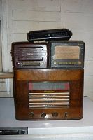 Stacked view of four vintage radios showing full wooden cabinet radio at bottom and three tabletop radios on top