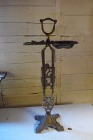 Front view of the full antique cast metal ash stand showing height, handle, and round ash tray.