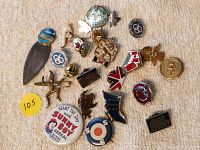 Photo showing multiple vintage pins arranged on a cloth surface, including promotional and emblematic designs.