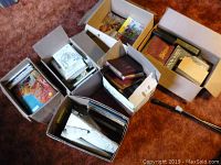 Several boxes filled with vintage and antique books and comic books placed on carpet.