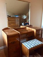 Photo of the vintage Art Deco style dresser with attached mirror and matching cushioned stool placed in front.