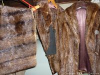 Photo showing multiple vintage brown fur coats and a fur stole or collar with a satin lining on hangers