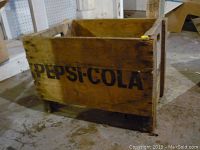 Side view showing Pepsi-Cola logo on wooden crate with wear and discoloration.