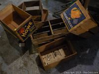Photo showing multiple vintage wooden fruit boxes including Howe Canadian Apples and Golden Cream crates stacked on a concrete floor.