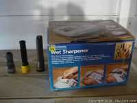 Wet Stone Sharpener box alongside three various flashlights showing front and top views.