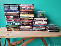 Photo showing stacked DVDs including Lost seasons, Friends season 1, Mad Men season 2, Boston Legal seasons, various movies like Kill Bill, Planet of the Apes, Deadpool, RoboCop