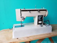 Off-white Eaton Viking portable sewing machine shown on wooden table with damaged power cord and missing foot pedal.