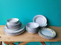 Wide view of various stacked dishware including a tall stack of bowls and several stacks of plates with floral designs.