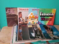Photo of lot showing front covers of multiple vinyl records in varying condition including Styx, Rod Stewart, Smurfing Singalong