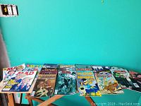 Wide view of multiple comic books and magazines laid out on a table including Mad Magazines featuring Donald Trump and Alfred E. Neuman, various comic books such as Jughead, Battlestar Galactica, and Scooby-Doo.