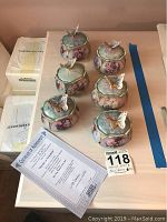 Six numbered porcelain music boxes with floral art and butterfly figures on lids, plus certificates and original packaging.