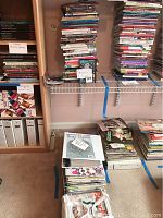 Wide shot showing shelves and stacks of books and magazines about beading and jewelry making.