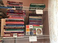 Shelves filled with multiple hardback quilting, patchwork, and applique instruction books, and some gardening books on top shelf
