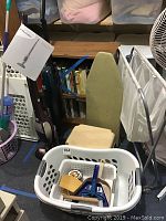Photo showing two cordless vacuum cleaners, a laundry sorter, a step stool, folding ironing board, plastic baskets with cleaning accessories.