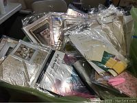 Multiple quilt patterns and pre-cut fabric kits in plastic bags, showing various quilting designs and fabric colors.