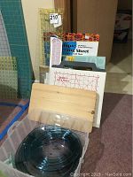 Overall set of quilting templates, cutters, boards, and rulers arranged on floor and leaning against wall