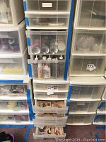 Photo of plastic storage drawers containing craft glues, adhesives, and multiple drawers filled with stamps.