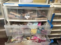 Top two drawers of plastic storage container filled with individually wrapped stamp kits and craft materials