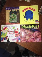 Four children's books laid out flat on a wooden table, showing front covers: "Too Many Frogs!", "Oswald", "I'm Gonna Like Me", and "Piggie Pie!"