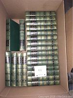 Box of 21 green hardcover Funk and Wagnalls encyclopedias, spines facing up showing volume titles and numbers.