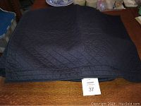 Navy blue diamond quilted twin-size bedspread laid flat on a surface, showing overall color and quilt pattern