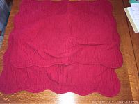 Folded red scalloped queen size quilted bedspread showing quilted pattern and scalloped edges