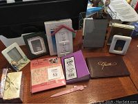 Full view of all contents in the lot arranged on a table showing photo albums, guest book, frames, letter opener, and keepsake box.