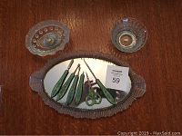Top view of the oval mirrored glass tray with five green handled grooming tools and button hook arranged across the mirror surface, flanked by two clear glass dishes.