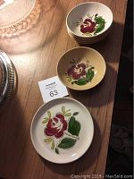 Photo showing stacked small sauce bowls with red rose and green/yellow leaf pattern.