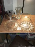 Full set showing lead crystal vase, glass cake plate with stainless steel dome, glass salad bowl, and glass deviled egg server on table.
