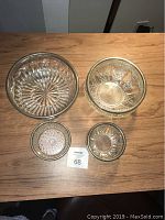 Top-down photo showing all four crystal bowls with metal rims on a wooden surface: two large bowls (9 and 8 inches diameter) and two smaller bowls (5 inches diameter).