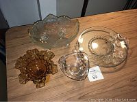 All four glass items displayed on a wooden table showing size and shape.