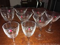 Nine glasses shown on table with red tape marks on some indicating possible chips or repairable damage.