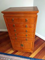 Front view showing four drawers with brass handles and double-door cabinet below on teak wood chest.