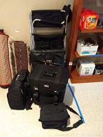 Full view of the lot showing four black items and the folding chair resting against the wall.