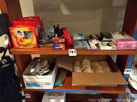 Shelves containing multiple boxes of Conair Pro clips, powder puffs in a box, packages of gloves, hair pins, and other beauty accessories.