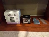 Lot items displayed on wooden shelf: boxed Iwata Silver Jet compressor, Temptu cleaner box, blue case with droppers, small cleaning tools in plastic bag.