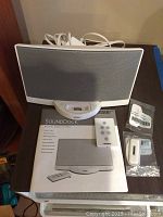 Bose SoundDock with remote control, user manual, two dock inserts, and power cable all displayed on a dark surface.