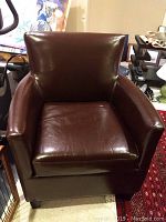 Front view of one dark brown faux leather chair showing cushioned seat and backrest