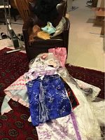 Photo showing multiple Lolita style dresses laid out on the floor and a chair with shoes and wigs on it.